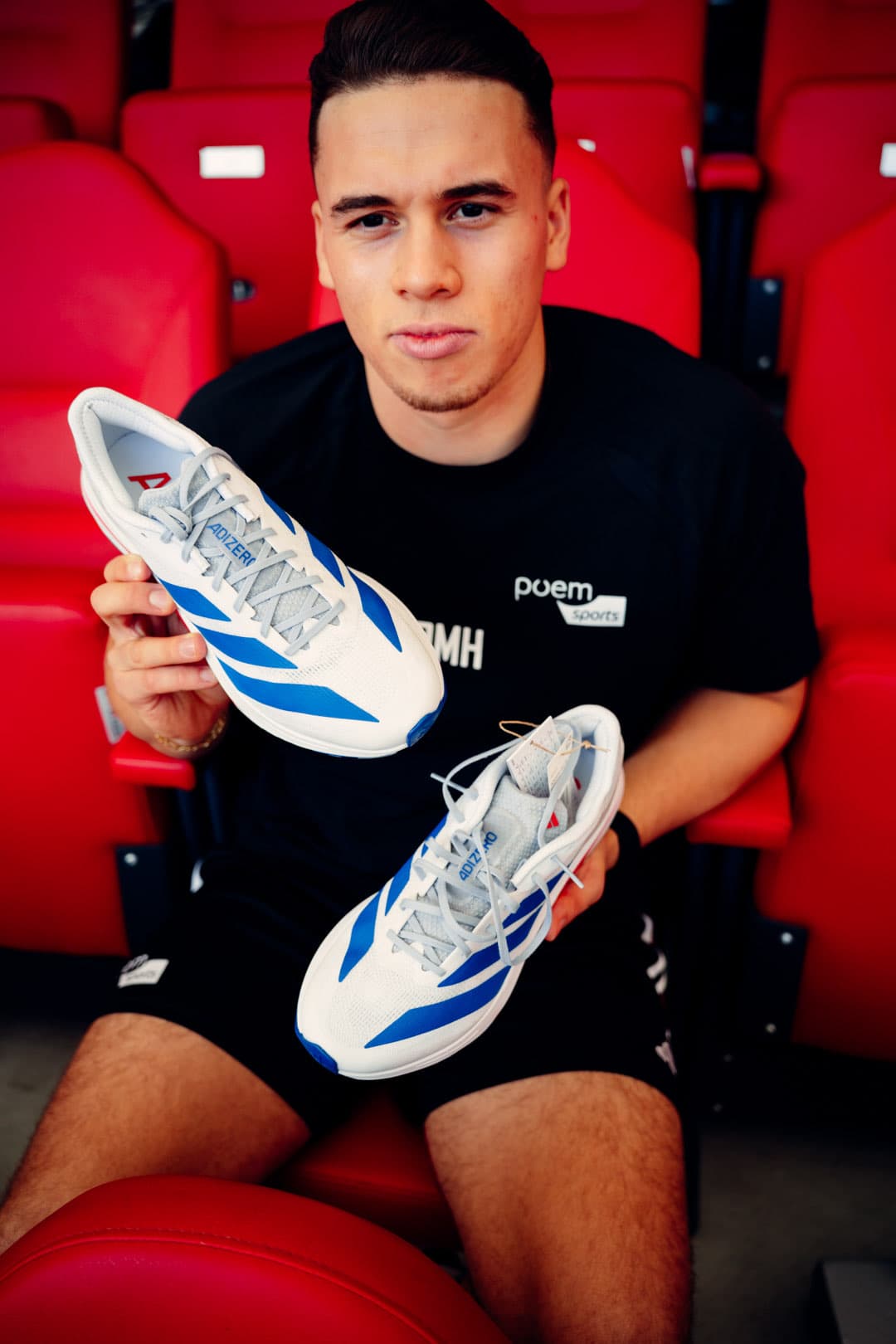 Phil auf den roten Sitzen der MHP Arena hält die weißen adidas adizero in die Kamera